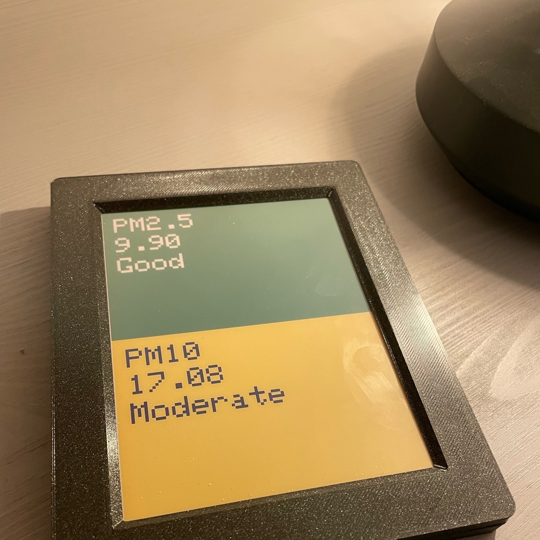 small e-ink tablet. top half of the screen says on green background PM2.5/9.90/Good. lower half has on yellow background PM10/17.08/Moderate. 